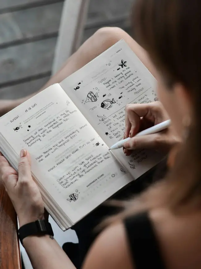ノートに英語で日記を書いている女性の手元の様子